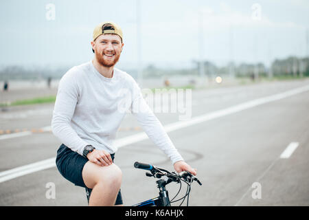 Businessman riding bicycle to work on urban street in morning Stock Photo