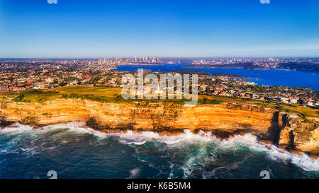 Sharp rugged sandstone rocky cliff off Australian continental plato facing open waters of Pacific ocean on a sunny bright day in aerial photo towards  Stock Photo