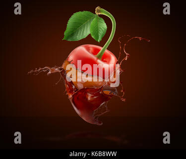 cherry in chocolate splash on a black background. Stock Photo