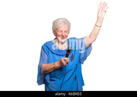 Older woman speaks or sings in a microphone isolated Stock Photo