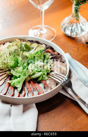 assorted meat on white plate on wood background. Stock Photo