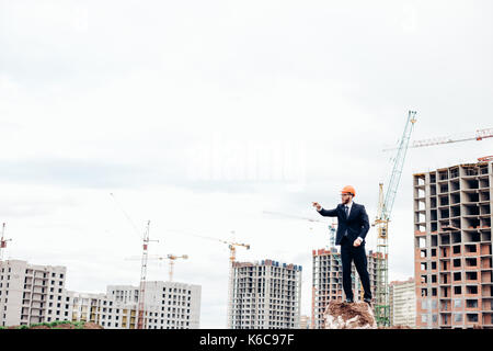 senior builder in hardhats pointing workers outdoors Stock Photo