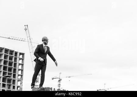 senior builder in hardhats pointing workers outdoors Stock Photo