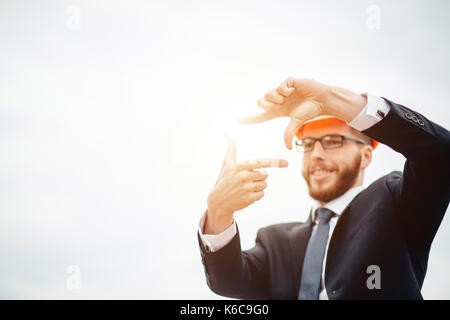senior builder in hardhats pointing workers outdoors Stock Photo