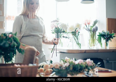 Florist at work: pretty young blond woman making fashion modern bouquet of different flowers Stock Photo