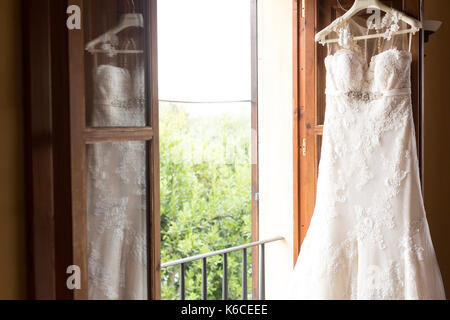 Wedding dress hanging on the balcony door Stock Photo
