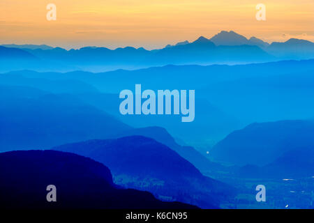 Aerial view on a landscape with mountain ridges and fog in the valleys at sunrise from Vogel cable car hill station at Lake Bohinj, Bohinjsko jezero i Stock Photo