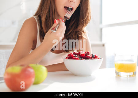Cropped image of a young casual woman eating fresh vegetables for breakfast indoors Stock Photo