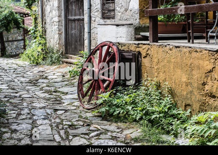 Wooden wheel in the old greek traditional village. Pretty village greek style - artwork in retro style. Stock Photo