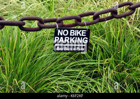 No Bike Parking Sign on a Large Chain with long grass in the Background Stock Photo