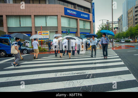 TOKYO, JAPAN JUNE 28 - 2017: Unidentified people under umbrellas on zebra crossing street in Jimbocho district located in Tokyo Stock Photo