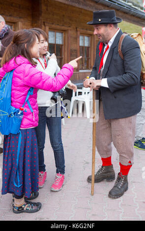 Two Asian tourists with traditionally dressed Zermatt local, Valais, Switzerland Stock Photo