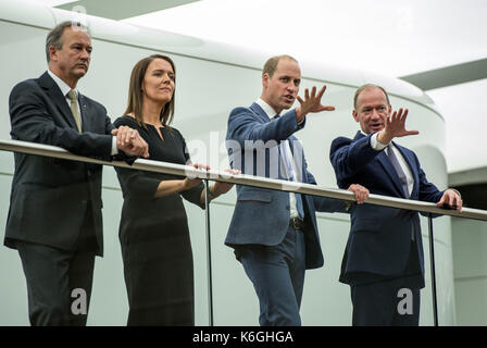 The Duke of Cambridge looks over the factory floor of the McLaren Production Centre with Jonathan Neale (left), chief operating officer of McLaren Technology Group, Ruth Nic Aoidh, executive director of commercial and legal, and Mike Flewitt (right), CEO of McLaren Automative, during a visit to the McLaren production centre in Woking, Surrey. Stock Photo