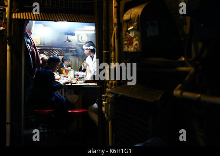 SHINJUKU, TOKYO, JAPAN - DECEMBER 2016 - Unidentified people eating in a small dinner shop in Shinjuku Stock Photo