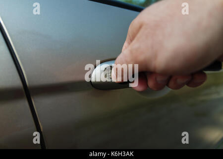 man's hand opens the car door with a key. Stock Photo