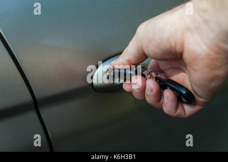 man's hand opens the car door with a key. Stock Photo