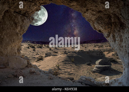 An unrealistic night landscape through a cave with milky, moon in eclipse, and desert with ruins of ancient columns. Stock Photo