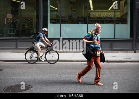 BOSTON, MA, USA - JUNE 2016 - Unidentified man dress in a colorfully way cross the street while an unidetified biker pass behind Stock Photo