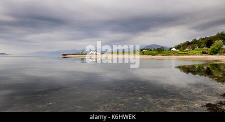 A house stands on a small peninsula, reflected in the calm sea on the shores of Loch Linnhe in the West Highlands of Scotland. Stock Photo