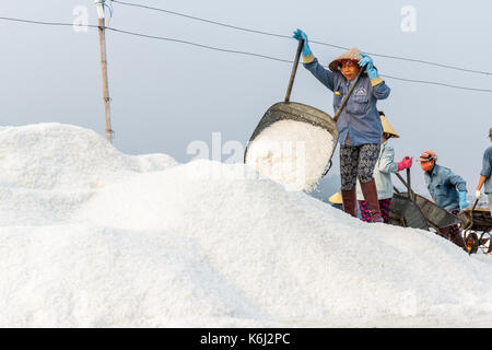 NHA TRANG, VIETNAM - 4/12/2016: A woman dumps salt at the Hon Khoi salt fields in Nha Trang, Vietnam. Stock Photo