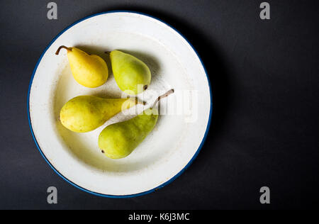 Green pears in a plate on  black background Stock Photo