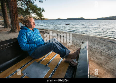 Woman sitting in renovated truck watching sunset, Payette Lake, McCall, Idaho, USA Stock Photo