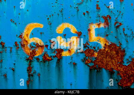 Abstract of painted blue metal covered in rust with numbers Stock Photo