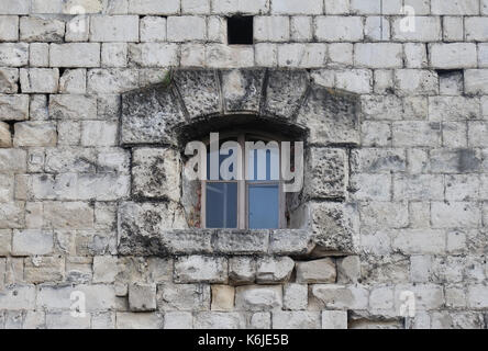 Small closed window on old stone building facade Stock Photo