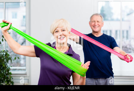 Elderly couple in senior gymnastic class doing workout with rubb Stock Photo