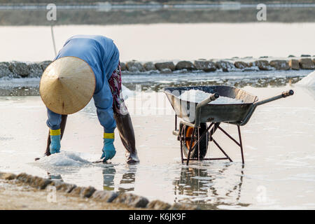 A woman gathers salt at the Hon Khoi salt fields in Nha Trang, Vietnam. Stock Photo