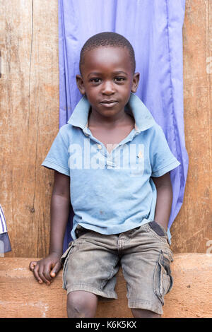 A little black boy sitting on a stair dressed in blue. Stock Photo