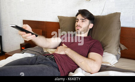 Handsome young man laying on his bed watching TV Stock Photo