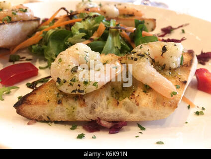 Italian Starter - Bruschetta Con Gamberetti - Marinated tiger prawns with garlic, basil and olive oil on toasted bread Stock Photo