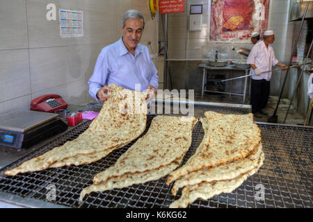 Fars Province, Shiraz, Iran - 18 april, 2017: The owner of the bakery considers freshly baked iranian lavash, prepared for sale. Stock Photo