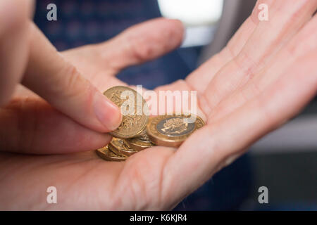 Picking out an old pound coin from a handful of new pound coins Stock Photo