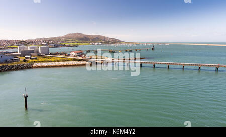 Piers and fuel tanks at Holyhead Port in North Wales, with Holyhead town and Holyhead Mountain behind. Stock Photo