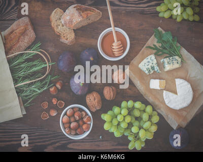 Sandwiches with ricotta, fresh figs, prosciutto, rosemary and blue cheese, walnuts and honey on rustic wooden board over black backdrop, top view. Del Stock Photo