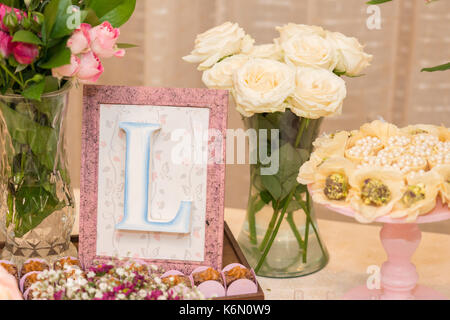 Front picture of letter L in a picture frames and milk candy dessert for woman party Stock Photo