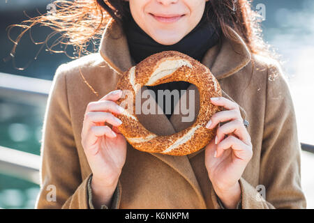 Beautiful woman holds a traditional Turkish simit in hands and wants to eat it Stock Photo