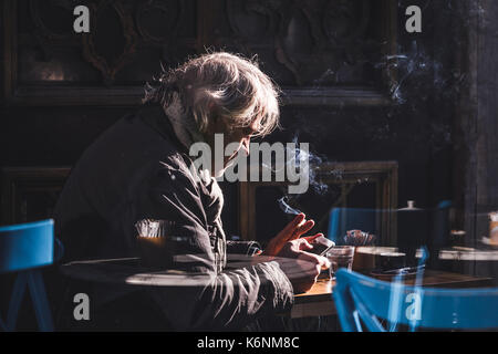 ISTANBUL, TURKEY - DECEMBER 10, 2016:  Gray-haired man drinks coffee and smokes in cafe Stock Photo