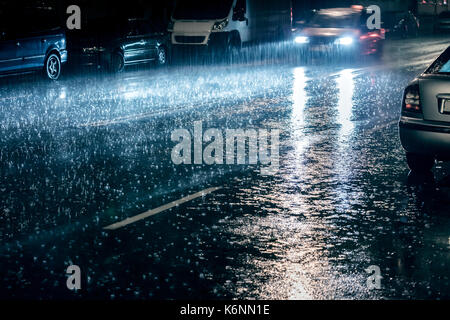 car in motion with switched on headlights driving during heavy rain Stock Photo