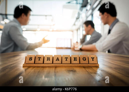 Strategy word on wood table with Business team work discussion together concept in background Stock Photo