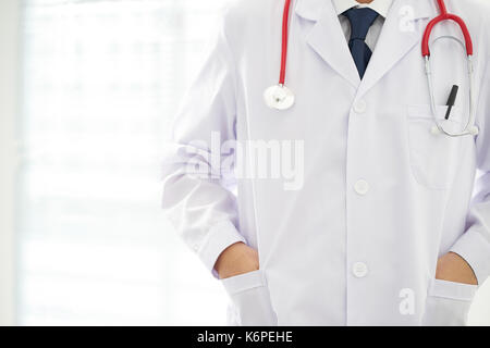 Unknown doctor posing two hand in pocket in the office, he is wearing a stethoscope . Stock Photo