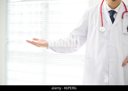 Unknown doctor posing pointing away advertising your product. Stock Photo