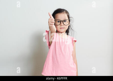 Little girl dressed in pink is showing thumb up gesture , isolated over white background . Stock Photo