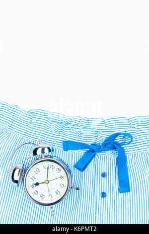 Striped blue pajama pants and an alarm clock in retro style, space from above Stock Photo