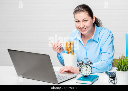 Businessman in a blue shirt eating noodles at his desk Stock Photo