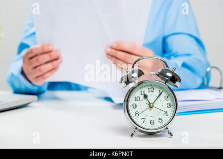 Accountant working in the office, alarm clock in focus close-up Stock Photo