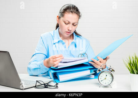 The financial analyst carefully examines the company's documents at the desk in the office Stock Photo
