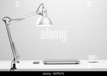 Empty workplace - white table and white brick wall Stock Photo